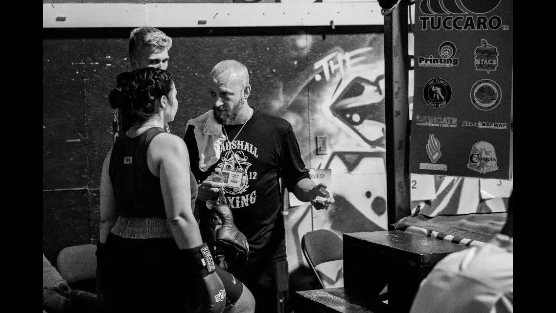 A Marshall Boxing coach giving a boxer advice before a bout