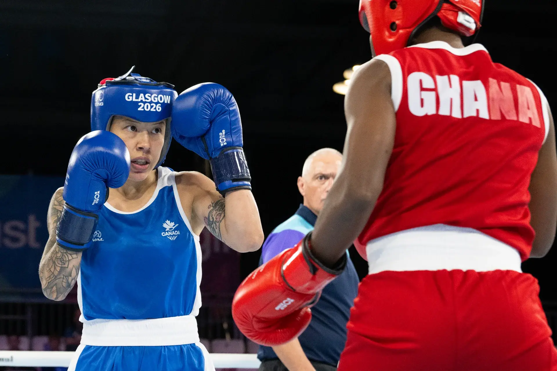 Boxer in blue Canada kit facing an opponent in red